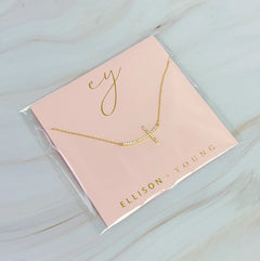 Gold necklace on a pink card with 'ELLISON YOUNG' branding on a light blue background